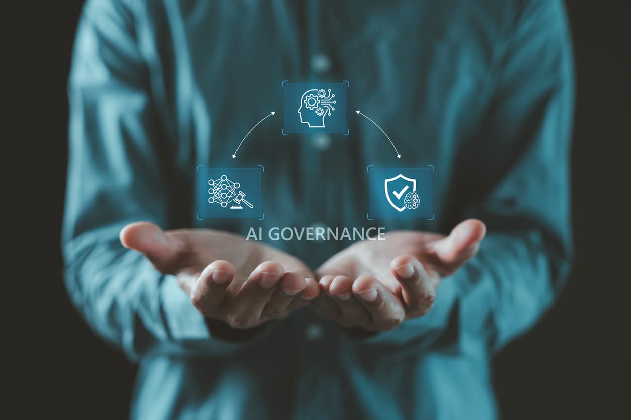 A person holds out open palms beneath floating holographic icons of a circuit brain, a gavel, and a shield around the words AI governance